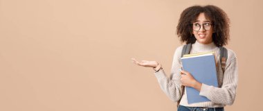 Modern eğitimin hataları ve sorunları. Sırt çantalı Afrikalı Amerikalı kadının elinde not defterleri var ve sarı arka planda izole edilmiş boş bir alan gösteriyor.