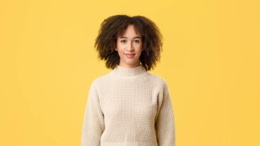 Sakin, güzel bayan öğrenci ve doğal duygular. Gülümseyen kıvırcık saçlı Afro-Amerikan kadın kameraya bak, sarı arka planda izole edilmiş, boş alan, kesilmiş, stüdyo çekimi