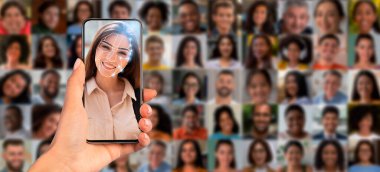 Bir el, yüz tanıma teknolojisini gösteren bir akıllı telefonu tutuyor, çeşitli portrelerin kolajına karşı insanların yüzünü vurguluyor, modern tanımlama yöntemlerini ve teknolojiyi sergiliyor.