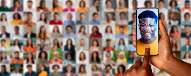 Bir el, gülümseyen bir bireyin yüz taramasını gösteren bir akıllı telefonu tutuyor. Bunun arkasında modern kimlik teknolojisini vurgulayan sayısız farklı insan portresi var..
