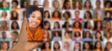 Aydınlık bir ortamda, bir kişi elinde bir akıllı telefon ile çeşitli portrelerin kolajı arasında gülümseyen bir yüz göstererek, tanıma teknolojisindeki gelişmeleri vurguluyor..