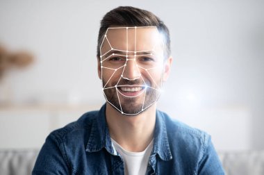 Yüz tanıma teknolojisi özelliklerini incelerken bir adam gülümsüyor. Bu, yeni güvenlik ve kolaylık normuna adapte olmak için gelişmiş tanımlama sistemleri kullanır.