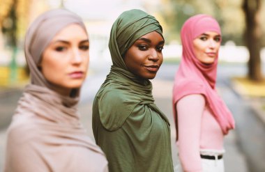 Modern Müslüman kadınlar. Üç farklı milenyum bayanı tesettüre girmiş açık havada kameraya bakarak poz veriyor. Arap genç kadın grup portresi. Seçici odak