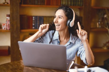 İşe ya da çalışmaya ara verdim. Kulaklık takan, müzik dinleyen, kişisel bilgisayarla masaya oturan neşeli dans eden ve ev ofisinde dinlenen genç bir kadın.