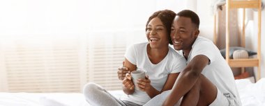 Mutlu siyah aile hafta sonları evde kalıyor, yatakta oturuyor, çay içiyor ve kitap okuyor, fotokopi odasına bakıyor. Neşeli Afrikalı Amerikalı çift birlikte eğleniyor, günlerini yatakta geçiriyorlar.