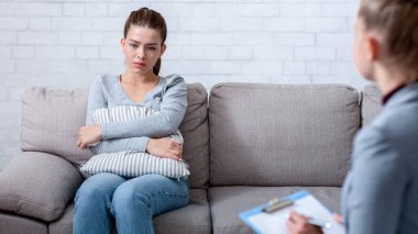 Travma sonrası stres bozukluğu çeken genç bir bayan danışmanlık bürosunda kanepede oturup yastığa sarılıyor. Depresyondaki kadın hasta psikoloğuna danışıyor, ruh hali bozukluğu tedavisi görüyor.