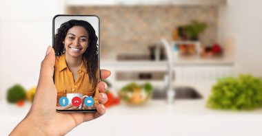 Bir insan, rahat bir mutfakta otururken akıllı telefondan yapılan bir video görüşmesinden zevk alıyor. Alıcı gülümsüyor ve nişanlı. Haberleşme kavramı