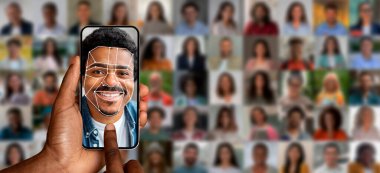 Bir el, gülümseyen bir adamın yüz tanıma taramasını gösteren bir akıllı telefonu tutuyor. Arkasında, gelişmiş tanımlama teknolojisini iş başında gösteren bulanık insan portreleri var..