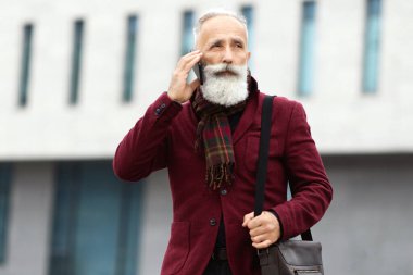 Yakışıklı, gri saçlı, uzun sakallı bir adam işten dönüyor, cep telefonuyla konuşuyor, deri çanta taşıyor, fotokopi odasına bakıyor. Yaşlı işadamı, telefon görüşmesi yaparak şehrin yanından geçiyor.