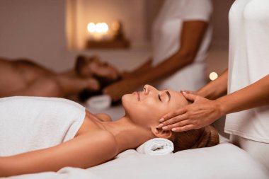 Spa 'da randevu. Birlikte kafa masajından zevk alan çift kapalı bir güzellik salonunda kapalı gözlerle yataklarda uzanırken masaj yapan vücut. Güzellik, Sağlık ve Rahatlama Seçici Odaklanma