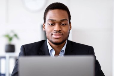 Ofiste dizüstü bilgisayarla çalışan, e-posta gönderen, iş stratejisi yazan, fotokopi çeken gözlüklü yakışıklı siyahi işadamlarının yakın çekimi. Genç Afro-Amerikan girişimci iş yerinde