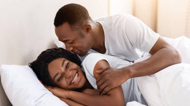 Mutlu Afro-Amerikalı çift evde yatakta dinleniyor, aşkta birlikte olmanın ve şefkatin tadını çıkarıyorlar, kopyalama alanında. Neşeli zenci aile babası ve aşık kadın yatak odasında eğleniyorlar.