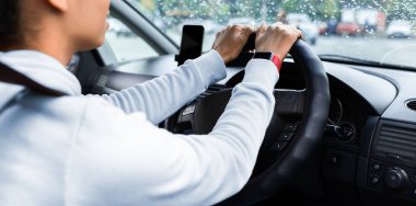 Şoför şehirde yeni bir araba sürmekten hoşlanıyor. Akıllı saati ve boş ekranlı akıllı telefonu olan neşeli, Afro-Amerikalı bir bayan direksiyonu tutuyor ve arabadaki yola bakıyor.