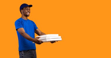 Hızlı Teslimat Servisi. Neşeli Afro-Amerikan kuryesi mavi şapkalı ve üniformalı. Restorandan pizza kutularını alıp bedava fotokopi alanına veriyor. Sarı arka plan, pankart, panorama.