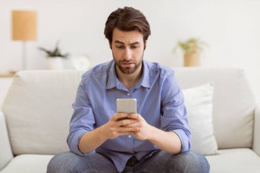 Sinirli Adam Cep Telefonu Mesajı Kullanıyor Kötü Haber Mesajı Okuyor İnternette Evdeki Kanepede Oturuyor. Smartphone 'la içeride vakit geçiren sıkkın adam. Seçici Odaklanma