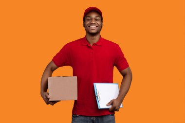 Paket alınıyor. Gülümseyen Afro-Amerikan Sakallı Teslimatçı Pano ve Karton Kutu, İyi Adam Mal ve Yiyecek Teslimatı, Turuncu Sarı Stüdyo Arkaplanının Üzerinde Duran
