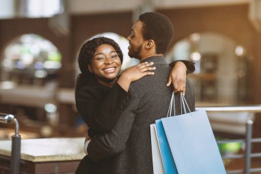 Afro-Amerikan çiftin alışveriş merkezindeki boş zamanı ve romantik randevusu. Mutlu adam ve kadın ceketli. Renkli çantalar taşıyorlar ve bir sürü alışveriş yapıyorlar. Ve Kara Cuma, boş yer.