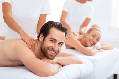 Spa Güzellik Merkezi 'nde birlikte uzanan neşeli bir çift boyun masajı yaptırıyor. Mutlu eşler, masajlarını yaparken dinleniyorlar. Evet. Romantik Spa Tatil Konsepti. Seçici Odaklanma