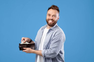 Havalı sakallı adam para dolu cüzdanı mavi stüdyonun arkasında tutuyor. Zengin milenyum adamı dolar gösteriyor, finansal başarısını paylaşıyor, maaş ve kar artışı konusunda mutlu.