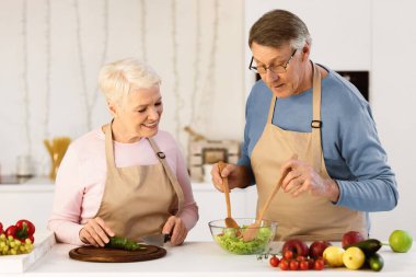 Olumlu yaşlı eşler akşam yemeği için sağlıklı sebze salatası hazırlıyor, evde modern mutfakta birlikte yemek pişiriyor ve diyet yapıyorlar. Yaşlılıkta Sağlıklı Beslenme