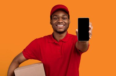 Teslimat Hizmeti Başvurusu. Gülümseyen Afro-Amerikan adam beyaz ekranlı akıllı telefon gösteriyor. Kırmızı başlık, üniforma ve termal çanta giyiyor.