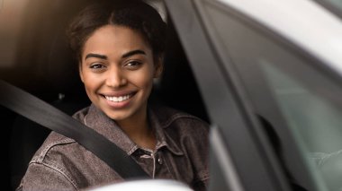 Büyük otomobil teklifi, araba reklamı ve modern blog yazarı. Gülümseyen mutlu Afro-Amerikan kadın direksiyonun arkasında oturuyor emniyet kemeriyle ve boş bir pencereden dışarı bakıyor.