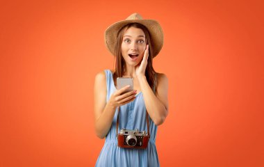 Sarı arka planda kameralı akıllı telefon ve kameralı şaşkın kız gezgin turistler için inanılmaz indirimler.