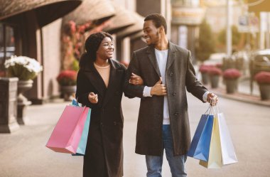 Şehirde iki kişilik yürüyüş ve alışveriş merkezinde alışveriş. Binlerce yıllık gülümseyen Afro-Amerikan karı ve koca renk çantalı son satıştan sonra iyi eğlenceler ve Kara Cuma mağazada, açık havada, kopyalama alanında