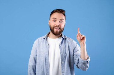 Yaratıcılık, fikir, ilham. Genç yakışıklı bir adam işaret ederek Eureka 'yı işaret ediyor. Mavi stüdyo arka planında AHA anı yaşıyor. Havalı sakallı adam zor sorunlara çözüm buluyor.