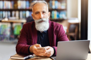 Kafede akıllı telefon kullanan, laptopun önünde oturan, öğle arasında serbest çalışan ya da e-posta gönderen yaşlı zengin bir adam. Kafede çalışan yaşlı işadamı, bilgisayar ve cep telefonu kullanıyor.