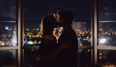 İki aşk nigth aydınlık şehir manzaralı panoramik pencere arka plan üzerinde öpüşme sonra silueti. Şehir kavramında seviyorum