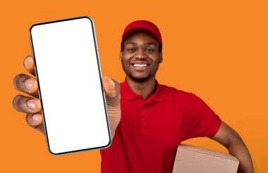 Teslimat Hizmeti Başvurusu. Gülümseyen Afro-Amerikan adam beyaz ekranlı akıllı telefon gösteriyor. Kırmızı başlık, üniforma ve termal çanta giyiyor.