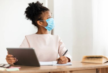 Koruyucu Yüz Maskeli Afrikalı Kız Sınıfta Tablet Bilgisayar Çalışıyor. Okula sağ salim dön. Seçici Odaklanma