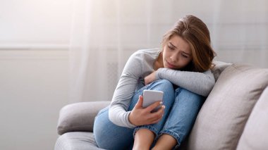Akıllı telefonuna bakan üzgün genç bir kadının portresi, siber zorbalık ya da mutsuz bir ilişkiden muzdarip, kötü bir ayrılık yaşıyor. Depresyon ve duygusal sorunlar kavramı