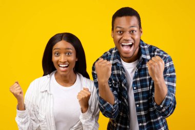 İnsani duygular ve çevrimiçi oyunda zafer. Şaşırtıcı başarılı genç Afro-Amerikan erkek ve kadın kahkahaları ve yumrukları zaferi kutluyor, sarı arka planda izole edilmiş, stüdyo çekimlerinde, kopyalama alanlarında