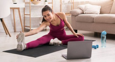 Kendini izole ederken aktif kal. Güzel bir kız evde dizüstü bilgisayar izleyip esniyor. Panorama