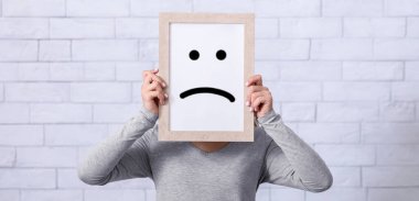 Depresyon, üzüntü, olumsuz duygu konsepti. Yüzünün önünde hüzünlü bir ifade olan çerçeveyi tutan genç bir kadın. Karamsarlık, yalnızlık, keder ve hüsranı ifade eden bin yıllık bir kadın.