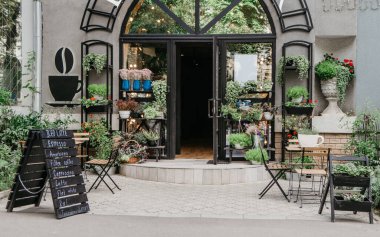 Sokak ve çiçek stüdyosundaki Eko kafe, şehirde küçük bir işletme, Coperid-19 'dan sonra tekrar açılıyor, iç mekan. Menü tahtası, müşteriler için masalar, modern mağazada raflarda saksı bitkileri, hiç kimse