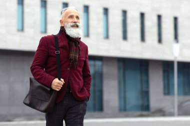 Şık bordo ceketli yaşlı gri saçlı mutlu bir adam sokakta tek başına yürüyor, işten eve dönüyor, gülümsüyor ve fotokopi odasına bakıyor. Emeklilik konsepti sırasında çalışmak, yaşlıların yaşam tarzı