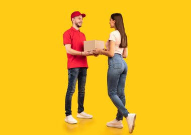 Sarı Stüdyo 'nun arka planında duran kadına paket kutusu veren kurye çocuk. Posta Paketleri Teslimatı, Paketler Taşıma Servisi Konsepti. Tam Uzunluk