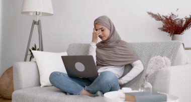Kötü amaçlı yazılım ve bilgisayar virüsü kavramı. Stresli müslüman kadın, virüsün yol açtığı hasarlı dizüstü bilgisayarla bağırıyor evde internet bağlantısı sorunu yaşıyor.