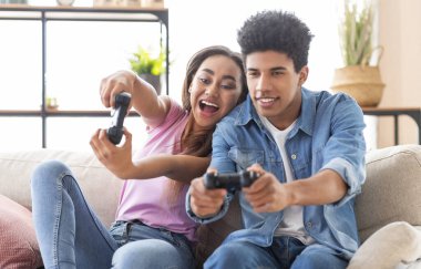 Mutlu siyah gençler kontrol pedi ile video oyunu oynarken, oturma odasında joysticks tutarak