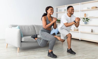 Atletik siyah çift antreman yapıyor, fotokopi çekiyor. Sportif Afro-Amerikan kadın ve erkek arkadaşı oturma odasında egzersiz yapıyorlar, panorama. Kapalı devre süresince ev içi eğitim
