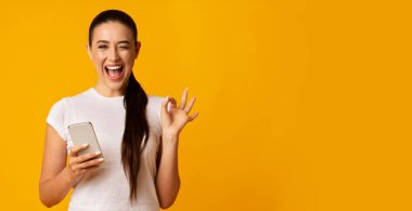 Kick Gadget Bağımlılığı. Millennial Girl Holding Cep Telefonu Ve Sargı Studio Arka Plan Üzerinde Ok Gesturing. Panorama, Boş Alan