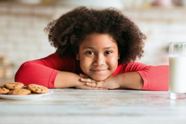 Kıvırcık Afro-Amerikalı kız kahvaltıda süt yerine kurabiye tercih ediyor.