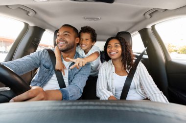 Güzel, sevecen Afro-Amerikan ailesi araba yolculuğunun tadını çıkarıyor. Babasını kucaklayan, araba kullanan, yola işaret eden, mutlu ebeveynler ve çocuklar hafta sonunu birlikte geçiren tatlı bir çocuk.