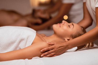 Spa Salonu 'nda, masörlerin yatağında gözleri kapalı uzanan ve çiftler için yapılan masajdan zevk alan bir kadın. Sağlık ve Masaj Terapisi, Vücut Rahatlığı Konsepti. Seçici Odaklanma, Düşük Işık