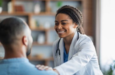 Cheerful attractive young african american woman doctor touching unrecognizable eastern man patient shoulder, general practitioner happy with results of treatment, supporting her patient, closeup