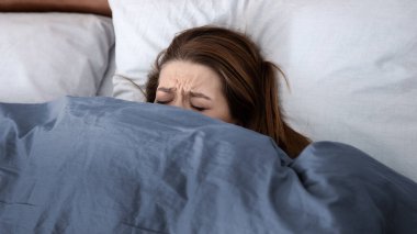 Akıl sağlığı konsepti. Bunalımlı genç bir kadın yatakta battaniyenin altında saklanıyor, depresyon, stres ya da uykusuzluk çekiyor. Mutsuz bir kadın kendini çaresiz ve yalnız hissediyor, psikolojik sorunları var.
