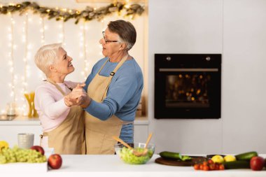 Happy Senior Couple Dancing In Kitchen At Home, Cooking Preparing Christmas Dinner Together And Having Fun. Retired Lifestyle Happiness, Older Family Holidays Concept. Copy Space